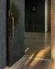 Baya Carla NZ wool floor mat in Military, styled at a dark entranceway beside an open door.