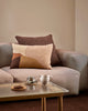 Baya Cortile lumbar cushion in Multi styled on a grey sofa with a solid brown cushion, beside a coffee setting on a glass and timber coffee table.