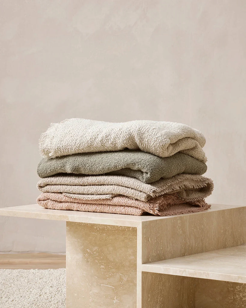 Pile of soft cotton-blend throw blankets in muted tones