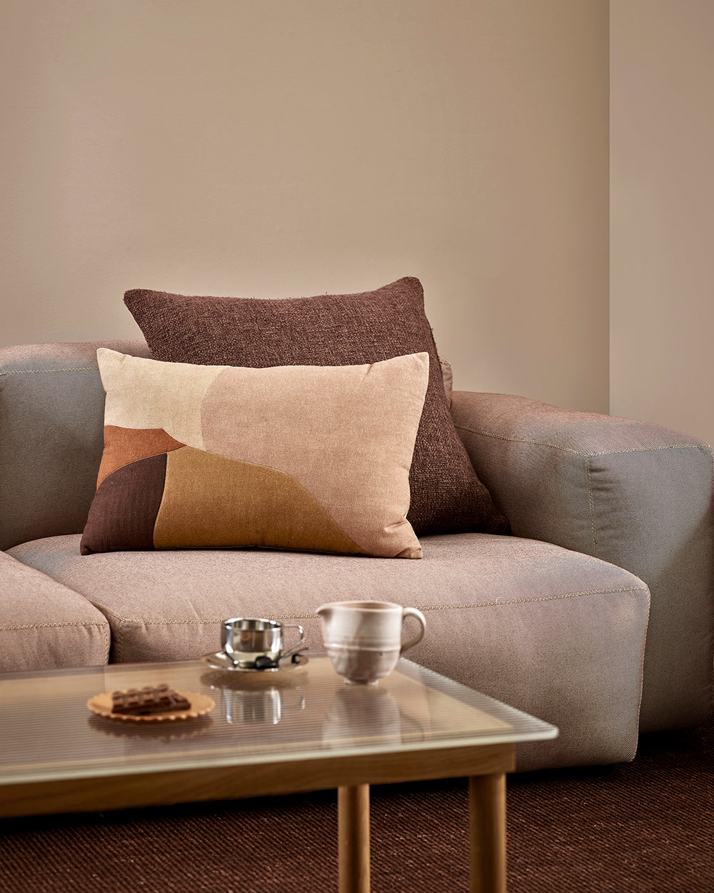 Baya Cyprian cushion in Espresso on a sofa, styled with a patterned lumbar cushion and a marble side table.