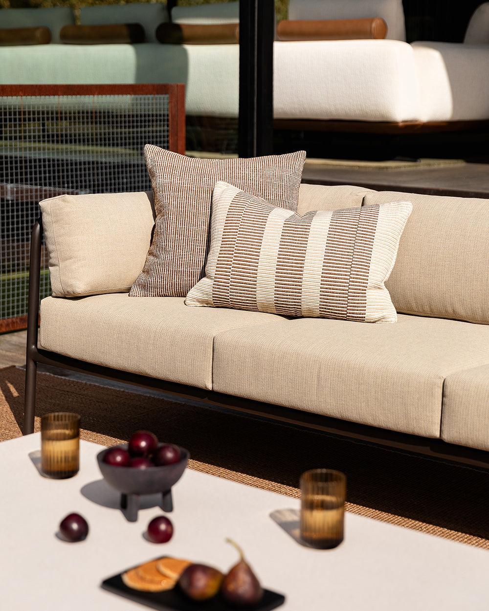 Baya Dune outdoor cushion in Tobacco styled on an outdoor sofa, wider view