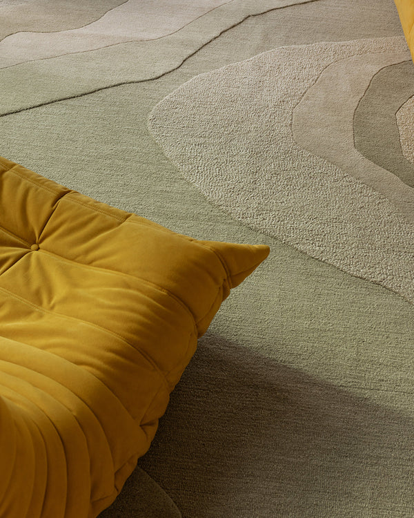 Baya Edgewater NZ wool floor rug in Pistachio, rectangle, close view of the wave pattern beside a mustard lounge chair.