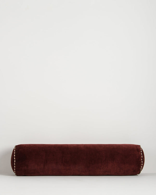 Baya Elliot cotton velvet bolster cushion in Oxblood on a plain background