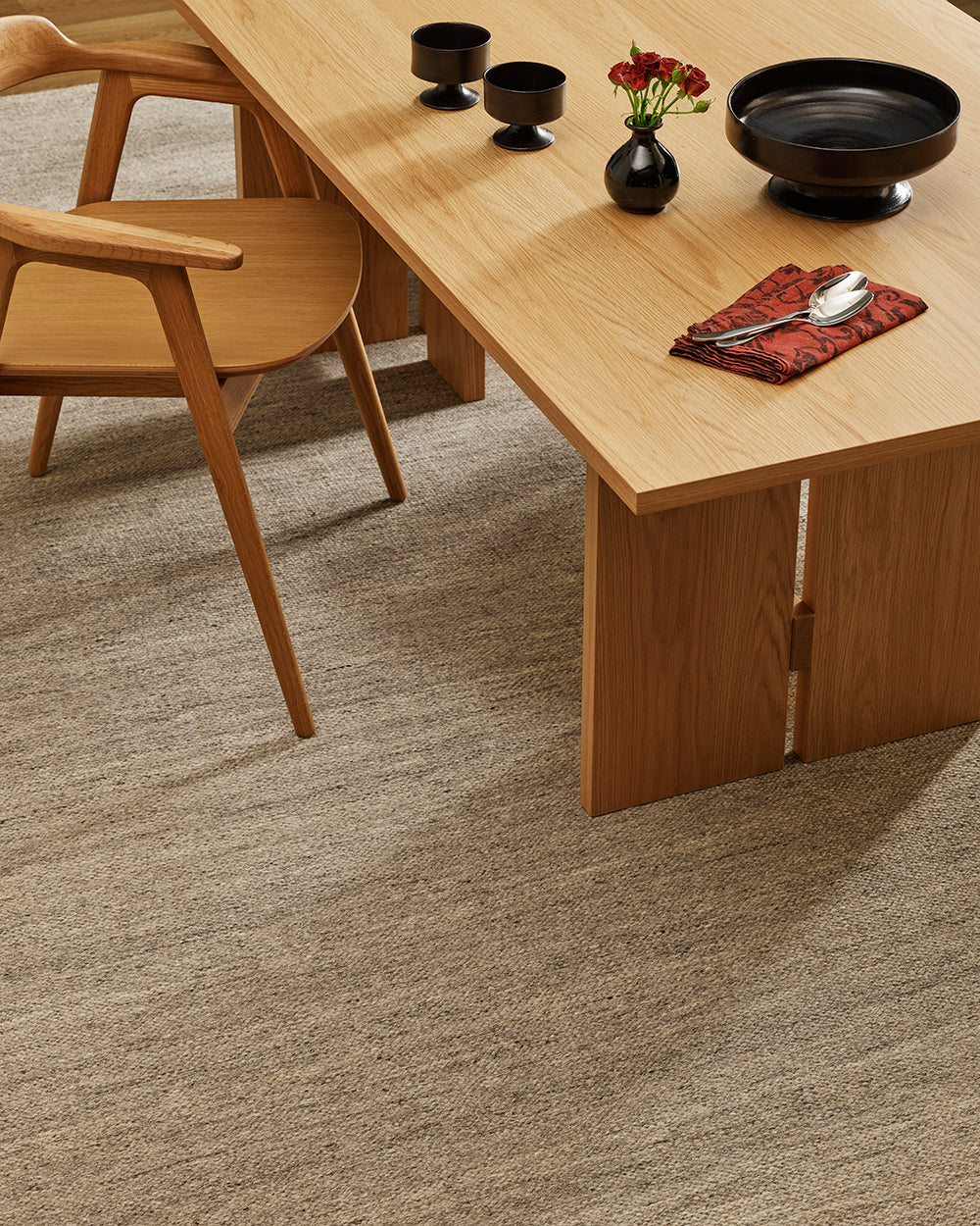 Baya Fairmont NZ Wool Floor Rug in Ash, close view under a dining table set with dark ceramics and a napkin