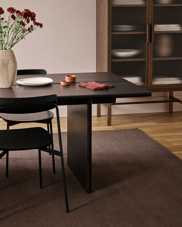 Baya Fairmont NZ Wool Floor Rug in Bracken, under a dining table with a vase of flowers and a glass-front cabinet