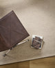 Baya Fairmont NZ Wool Floor Rug in Limestone, overhead view beside a leather chair with books