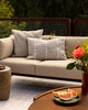 Baya Shore outdoor lumbar cushion in Almond styled on an outdoor sofa, with a second textured cushion in the background