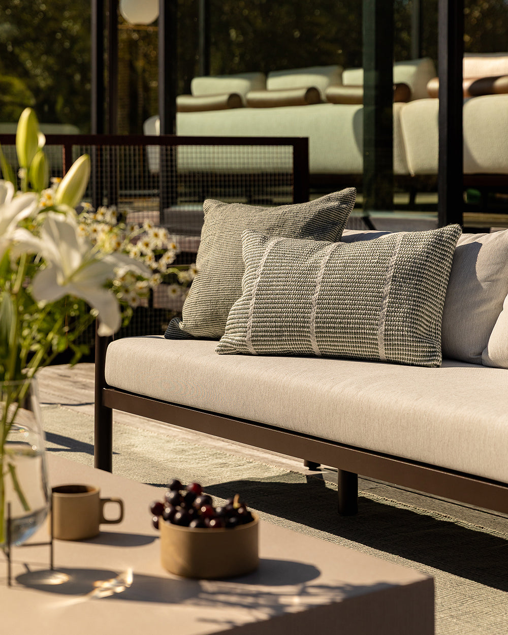 Close-up lifestyle shot of the Baya Shore outdoor lumbar cushion in Eucalyptus on a patio chair