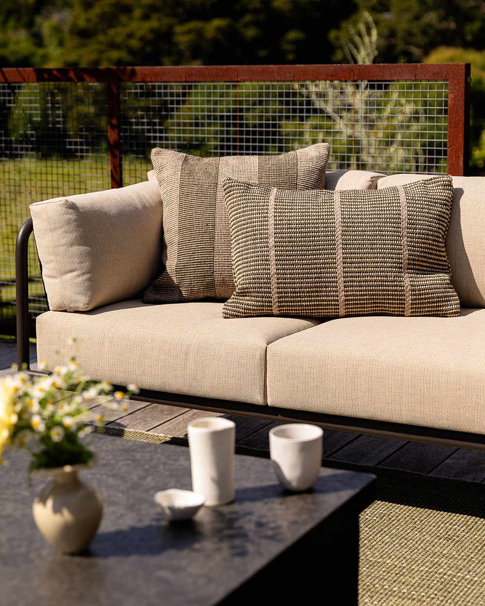 Close-up lifestyle shot of the Baya Shore outdoor lumbar cushion in Mangrove on an outdoor chair