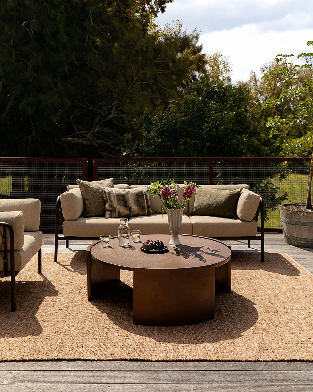 Baya Shore outdoor lumbar cushion in Mangrove styled on an outdoor chair at a round table setting