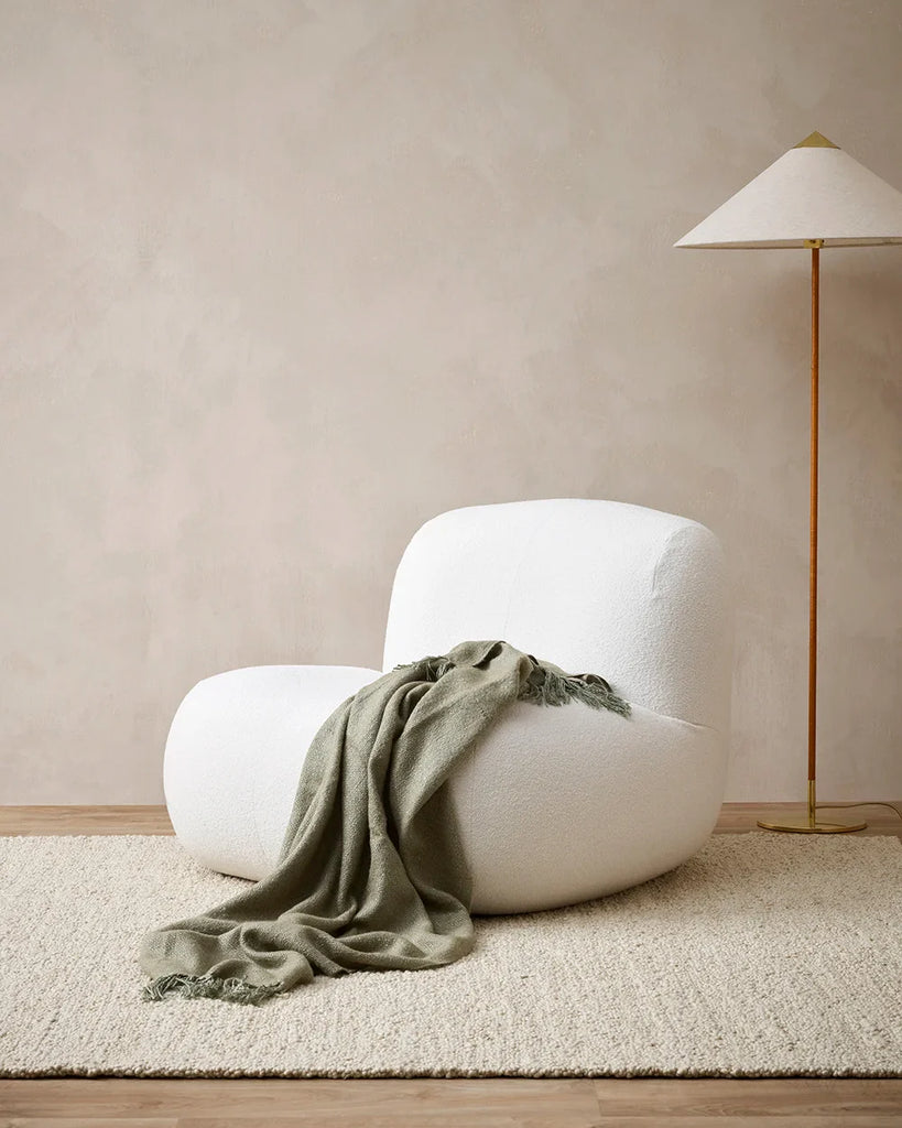 Green 'Richmond Sage' throw blnaket by Baya, draped on a chair in a modern lounge room