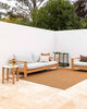 A warm brown basketweave rug by Baya NZ, shown in a sophisticated modern courtyard with couches. 