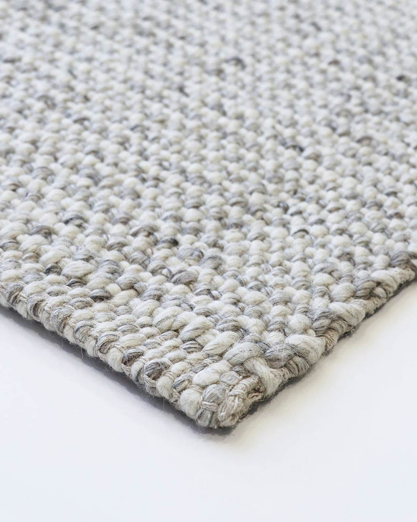 Close up view of the corner of a Baya NZ rug in cool toned weave.