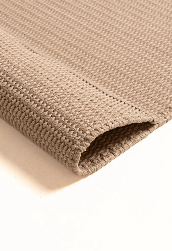 By Carmont Bisque rug in Cameo, folded corner showing the woven pile and backing