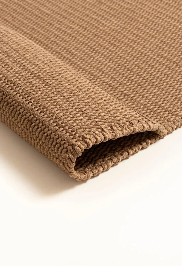 By Carmont Bisque floor rug in Natural, close-up of the folded corner showing the woven texture and finished edge