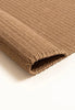 By Carmont Bisque floor rug in Natural, close-up of the folded corner showing the woven texture and finished edge
