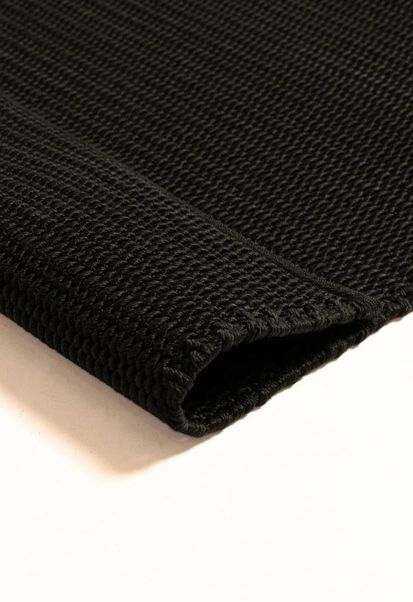 By Carmont Bisque floor rug in Sable, close-up of the folded corner showing the woven texture and finished edge