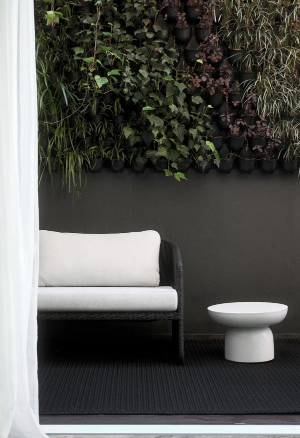 By Carmont Bisque floor rug in Sable styled on a covered outdoor patio