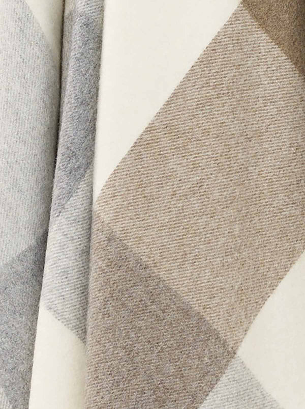 A close up of the weave of a 100% merino wool throw blanket in warm neutral tones. 