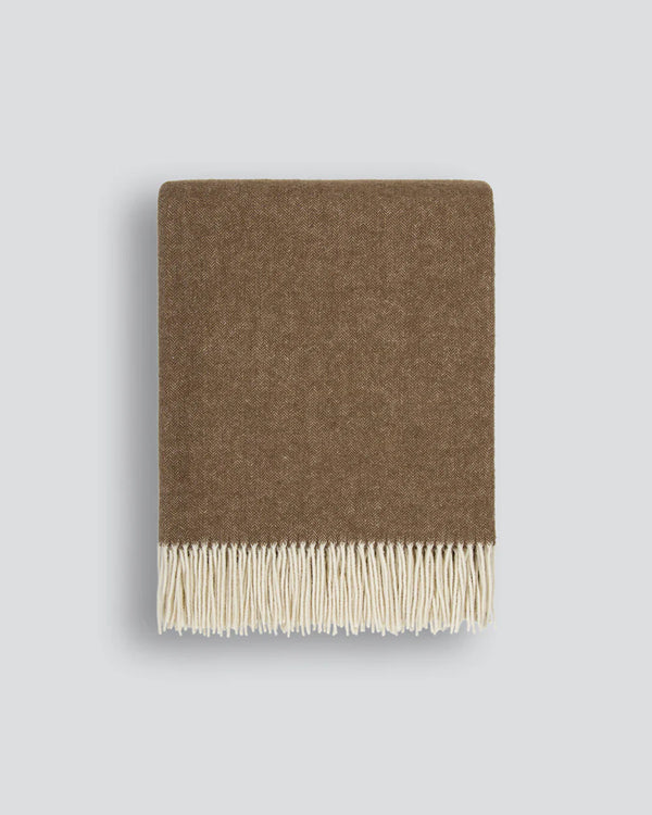 Brown wool blanket in a micro herringbone pattern with fringe on a light grey background