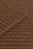 By Carmont Aman floor rug in Coffee, diagonal view showing the braided weave with the edge binding crossing it.