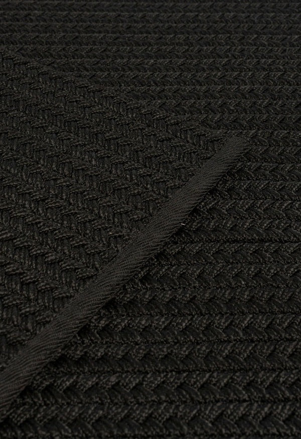 By Carmont Aman Floor Rug in Sable, close-up of the weave with the binding edge across the diagonal