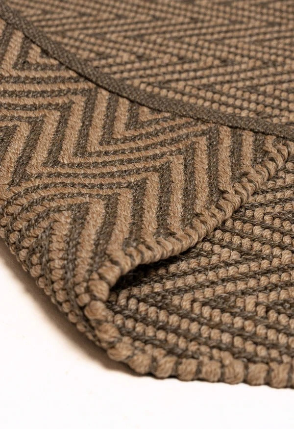By Carmont Bhumi Floor Rug in Umber, folded corner showing the woven edge binding