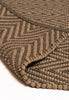 By Carmont Bhumi Floor Rug in Umber, folded corner showing the woven edge binding