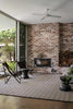 By Carmont Bhumi Floor Rug in Umber styled in an indoor-outdoor living room with a brick fireplace