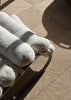 By Carmont Capella floor rug in Natural underfoot beside a cream bouclé lounge chair in natural light