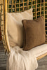 By Carmont Huxley cushion cover in Cameo on a hanging chair, behind a brown cushion with a pale throw