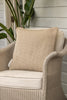 By Carmont Huxley cushion cover in Cameo on a pale wicker armchair against a weatherboard wall