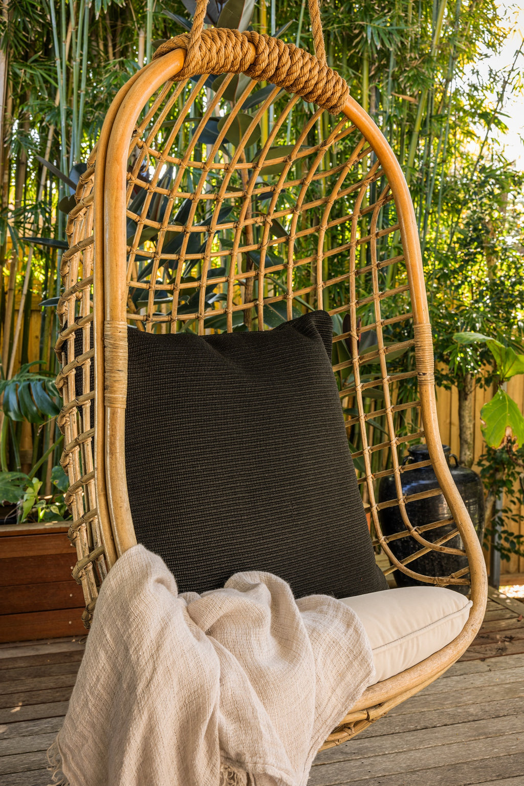 By Carmont Huxley cushion cover in Sable on a hanging chair, with a pale throw over the seat