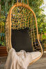 By Carmont Huxley cushion cover in Sable on a hanging chair, with a pale throw over the seat