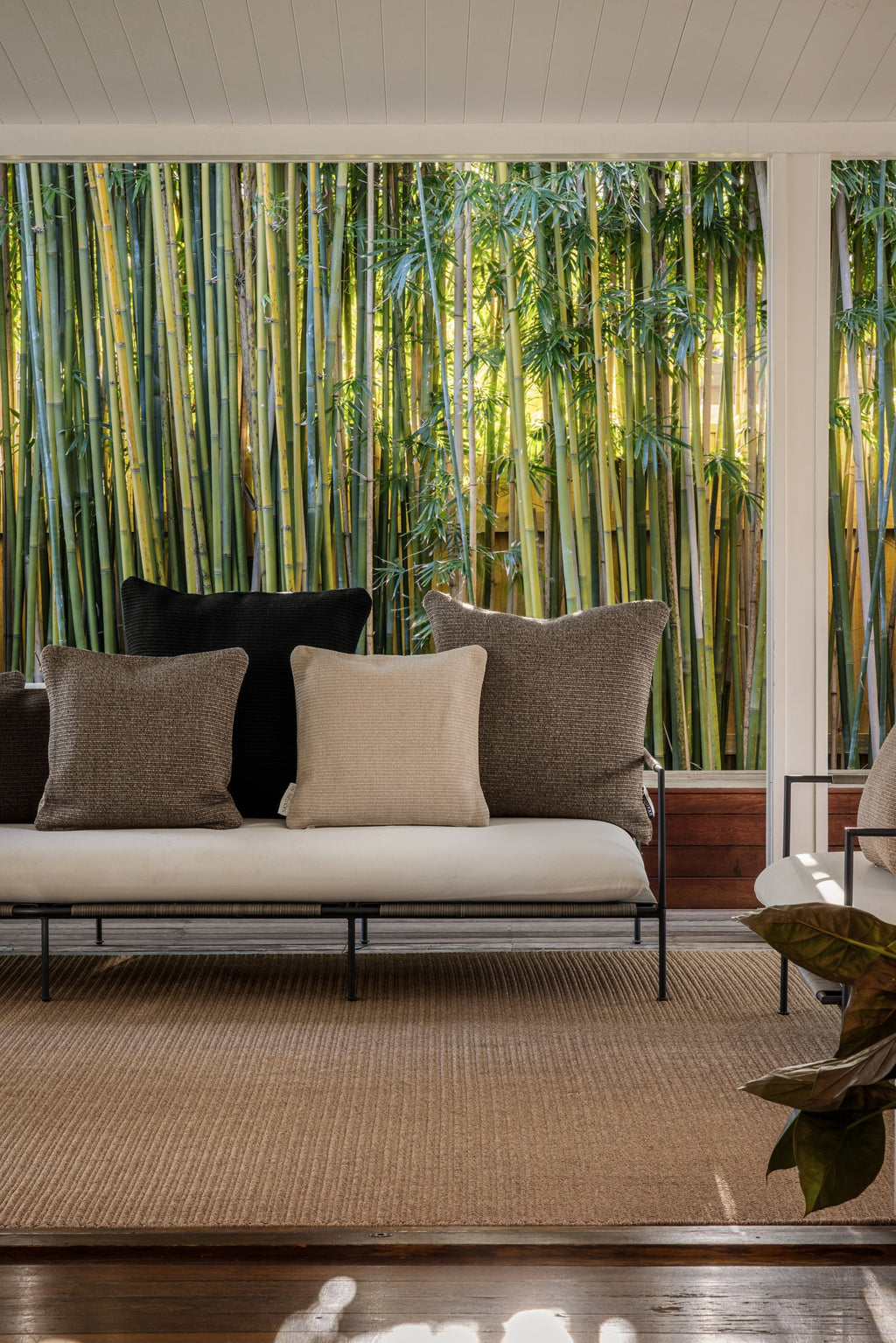 By Carmont Huxley cushion cover in Sable at the back of an outdoor sofa, with brown and pale cushions in front