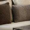 By Carmont Leroy cushion cover in Topaz on a sofa beside a darker brown cushion, with pale cushions behind