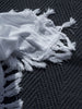 By Carmont Sapphire floor rug in Ambrosia, close view of the weave with a fringed throw laid over it.