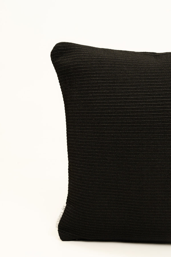 By Carmont Wren cushion cover in Sable, corner close-up showing the woven texture and brand label
