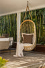 By Carmont Wren cushion cover in Topaz on a hanging chair, wide view of a covered deck and outdoor sofa