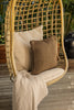 By Carmont Wren cushion cover in Topaz, close view on a hanging chair with a pale cushion and throw