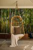 By Carmont Wren cushion cover in Topaz on a chair hanging from the ceiling of a covered deck