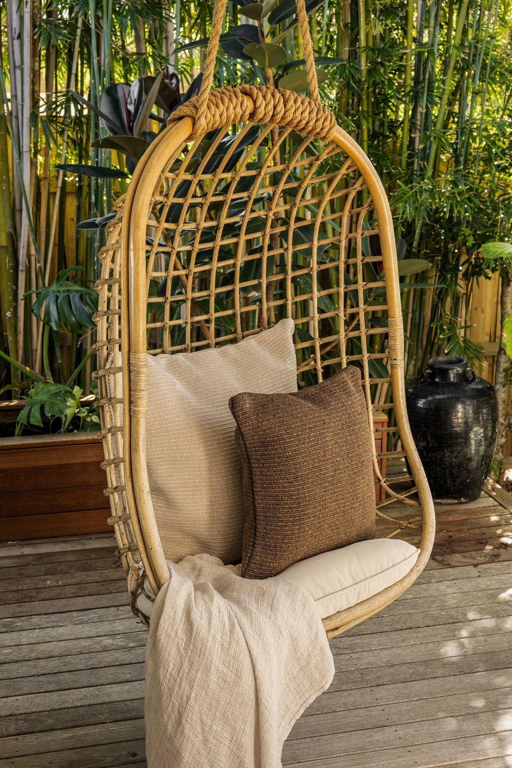 By Carmont Wren cushion cover in Topaz on a hanging chair, in front of a larger pale cushion