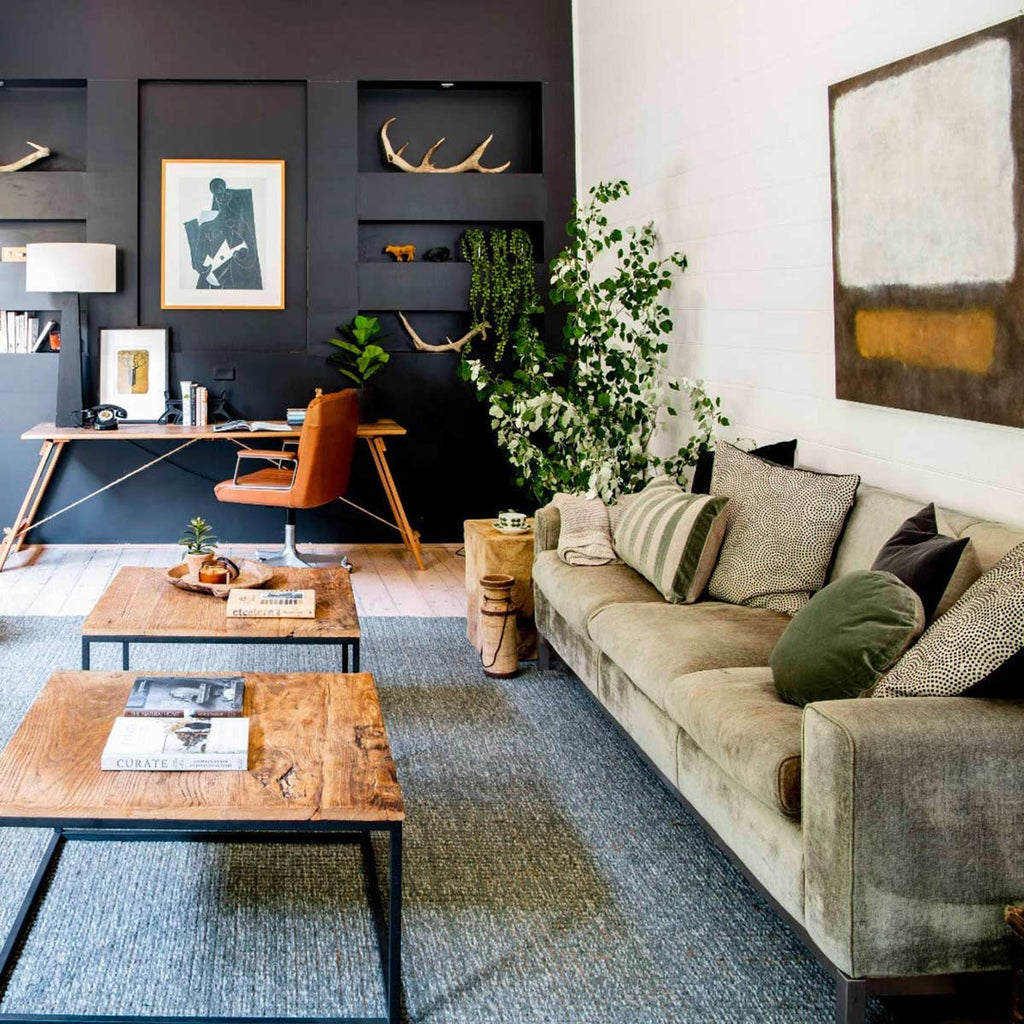 A bohemian living room decorated in earth tones with a cosy looking couch and a forest green textural jute and wool rug. 