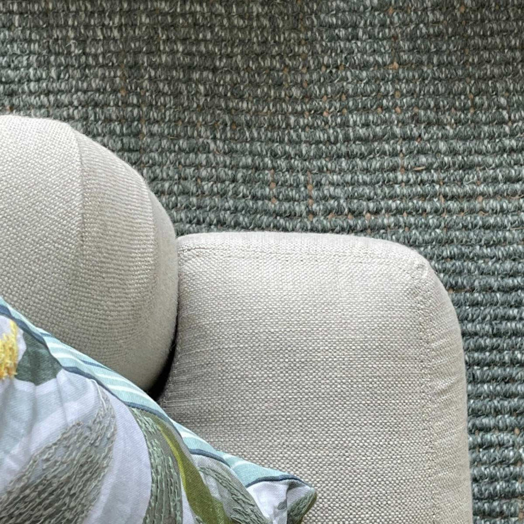A close up of the boucle weave of a green wool and jute blend rug. 