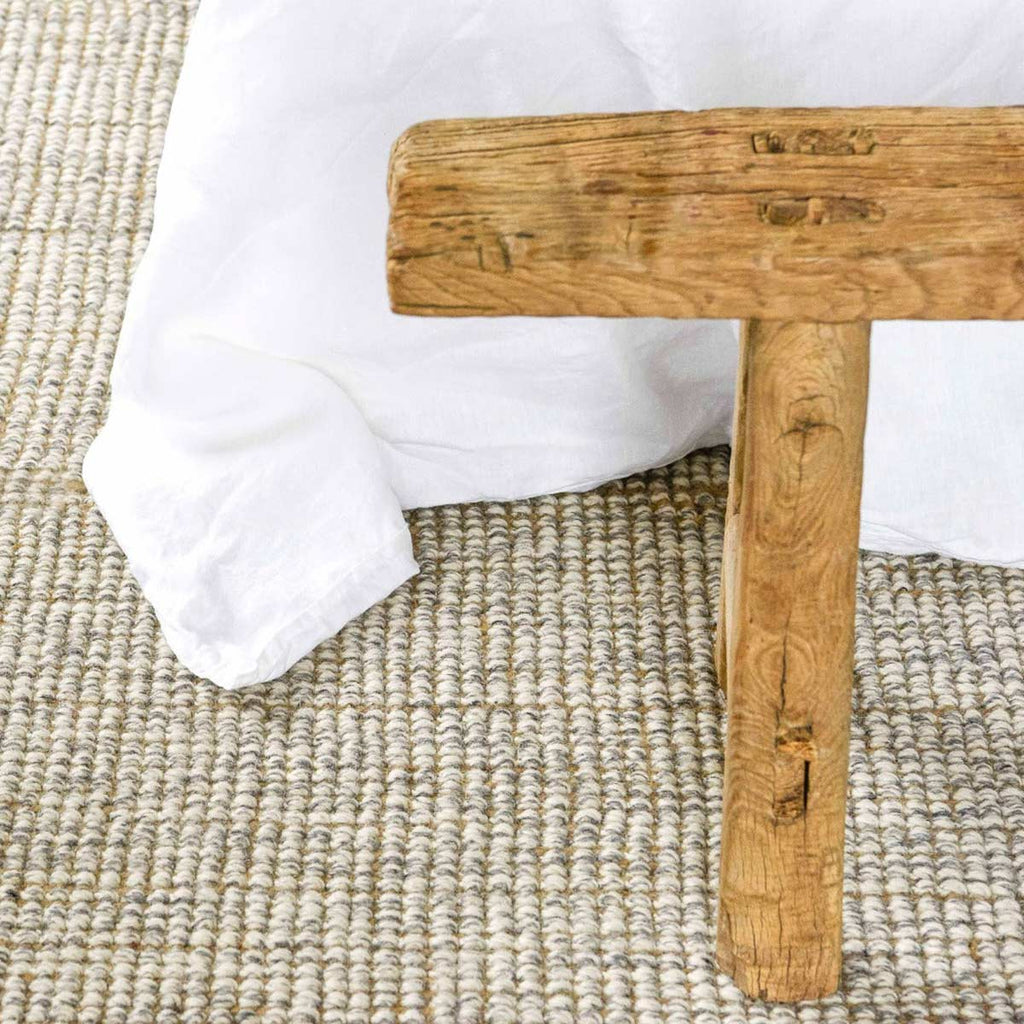 A close up of the boucle weave of a cream floor rug made of jute and wool. 