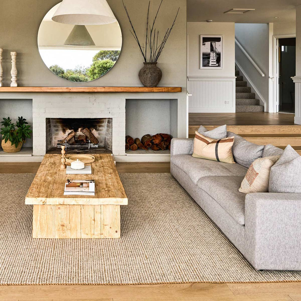 A bohemian living room with a large floor rug in neutral shades of cream and brown, made from a blend of natural jute fibres and wool. 