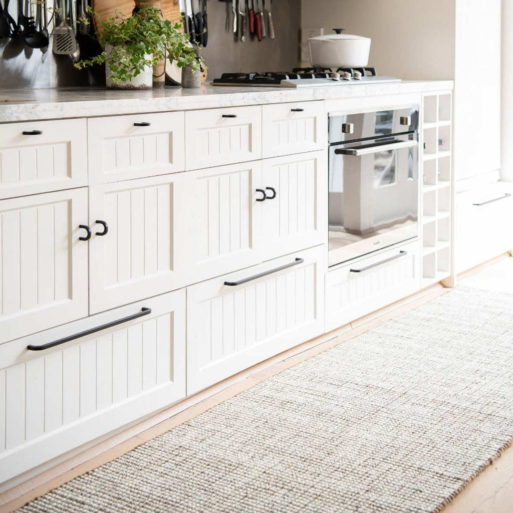 A white themed modern kitchen with a kitchen runner in complimentary shades of brown and cream, made from durable jute and wool fibres. 
