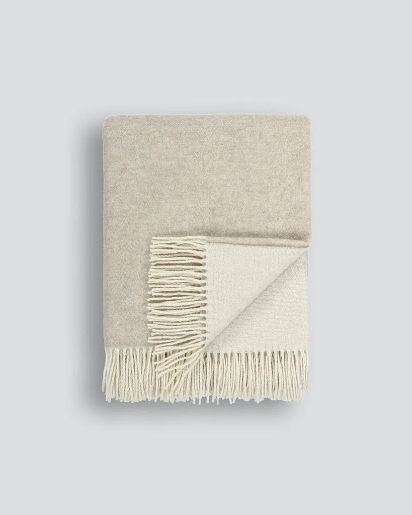 A two-toned reversible cream and oatmeal merino-bland throw blanket by Baya