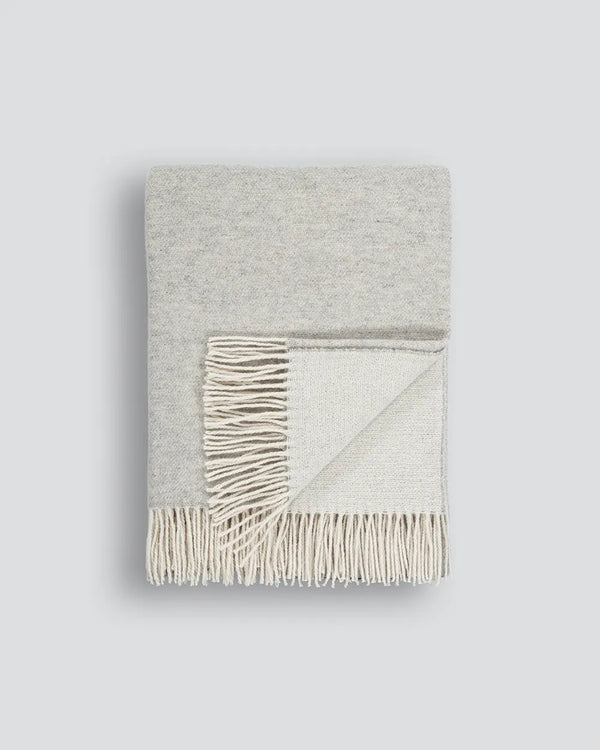 Light grey merino-blend throw blanket with tasselled fringe