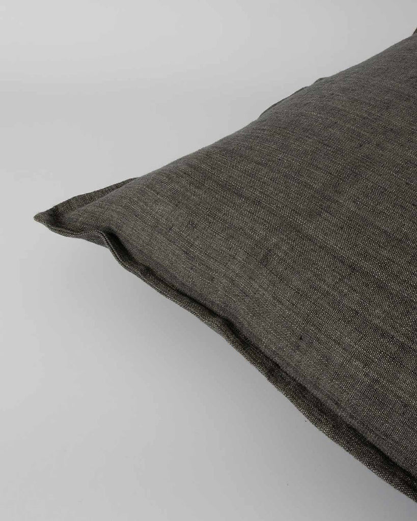 The edge of a handwoven linen cushion by Baya, in the shade Nori, a beautiful dark green.